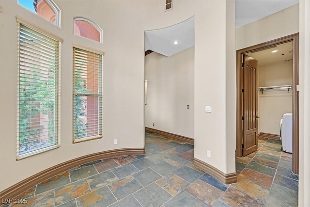 unfurnished room with washer / clothes dryer, visible vents, stone tile floors, and baseboards