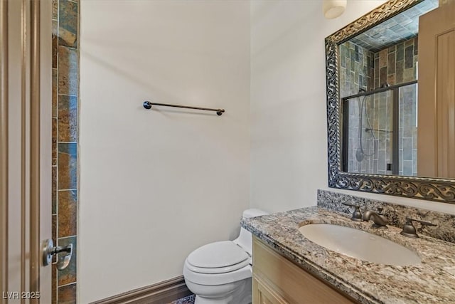 bathroom with toilet, tiled shower, and vanity