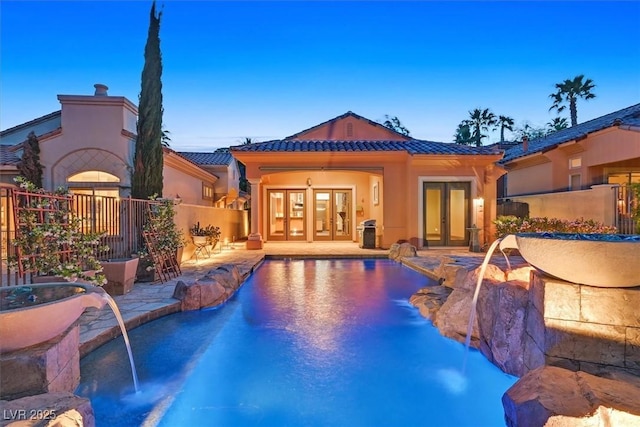 back of house with a tile roof, a patio area, a fenced in pool, french doors, and fence