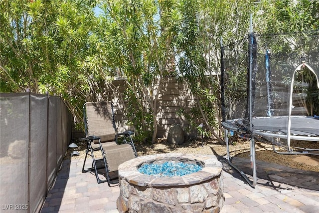 12254 Cape Cortez Ct, Las Vegas, NV 89138 - view of patio / terrace featuring a trampoline, a fenced backyard, and an outdoor fire pit