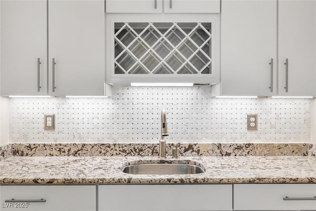 12254 Cape Cortez Ct, Las Vegas, NV 89138 - kitchen with white cabinets, backsplash, light stone counters, and a sink