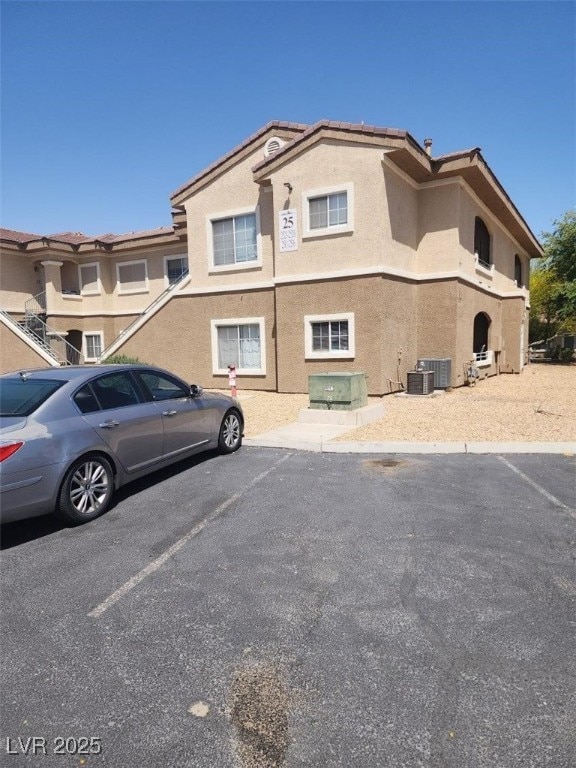 exterior space featuring central AC unit, stucco siding, and uncovered parking