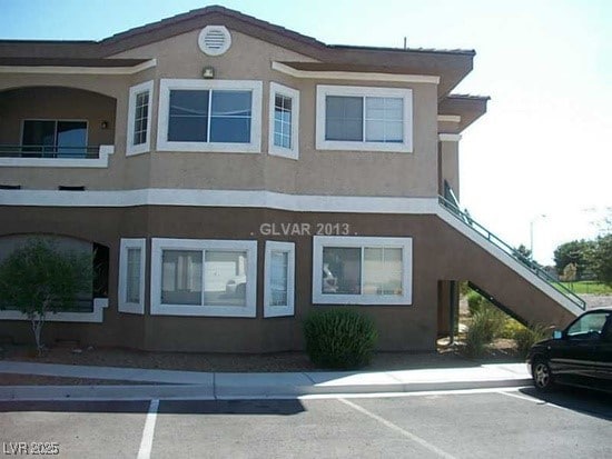 exterior space featuring uncovered parking, stucco siding, and stairway