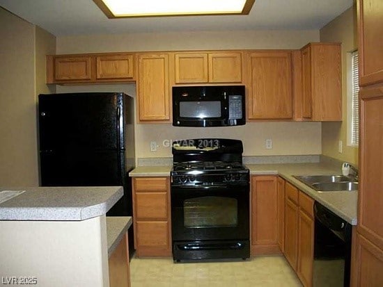 kitchen with a sink, black appliances, and light countertops