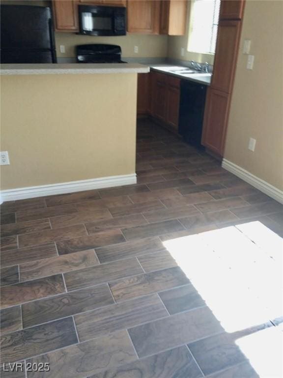 kitchen with light countertops, baseboards, a sink, and black appliances