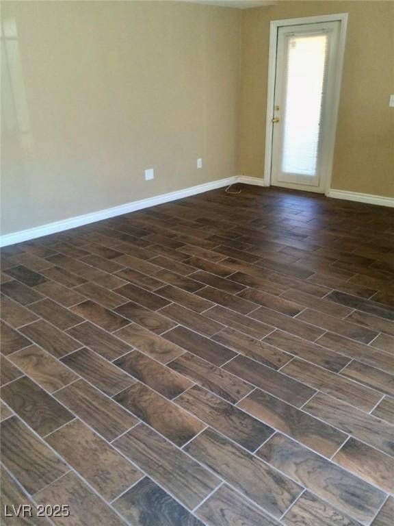 unfurnished room featuring baseboards and dark wood finished floors