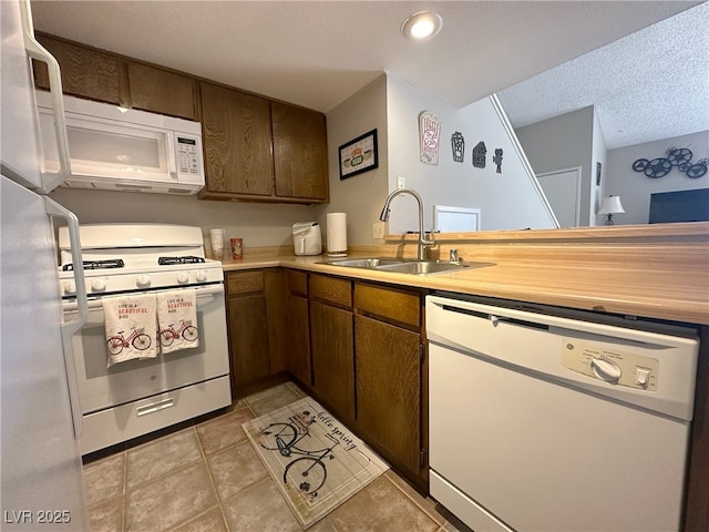 kitchen featuring white appliances, light tile patterned flooring, light countertops, and a sink