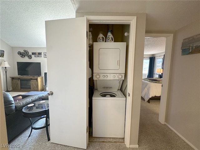 washroom featuring laundry area, stacked washer / dryer, carpet flooring, baseboards, and a textured ceiling