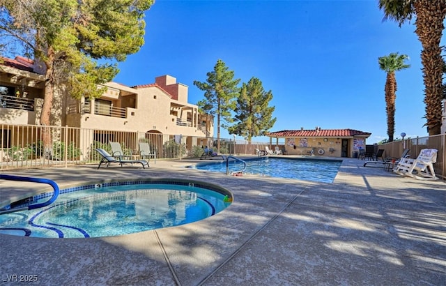 community pool with a patio area and fence