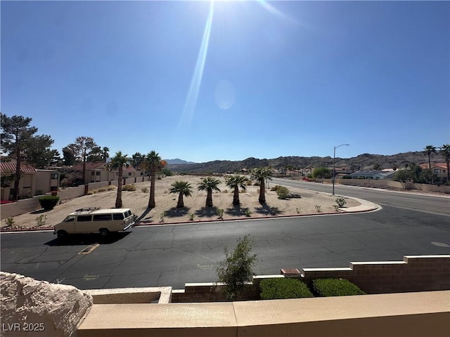 view of road featuring sidewalks, curbs, street lighting, and a mountain view