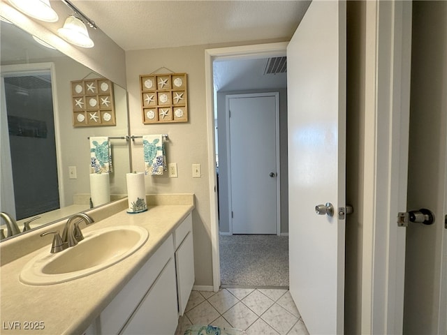 bathroom with a textured ceiling, visible vents, baseboards, tile patterned floors, and vanity