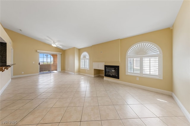 7950 W Flamingo Rd Unit 2066, Las Vegas, NV 89147 - unfurnished living room with a ceiling fan, a glass covered fireplace, vaulted ceiling, light tile patterned floors, and baseboards