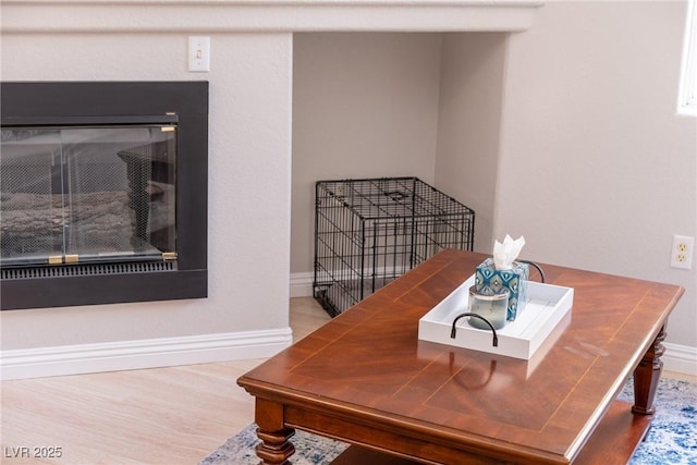 office space featuring a glass covered fireplace, wood finished floors, and baseboards