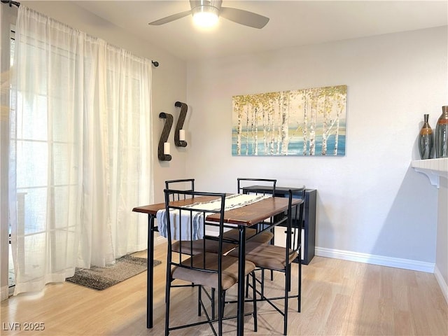 dining space with a ceiling fan, wood finished floors, and baseboards