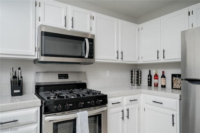 kitchen with white cabinetry, tile counters, and appliances with stainless steel finishes
