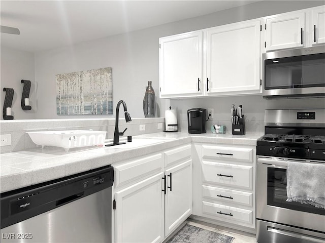 kitchen featuring a sink, appliances with stainless steel finishes, decorative backsplash, and white cabinetry