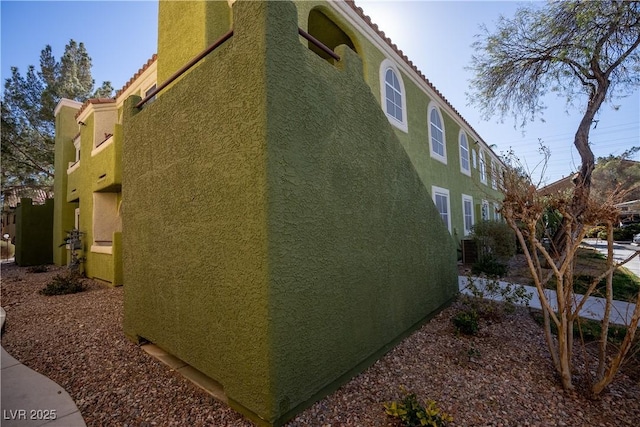 view of side of home featuring stucco siding and a tiled roof