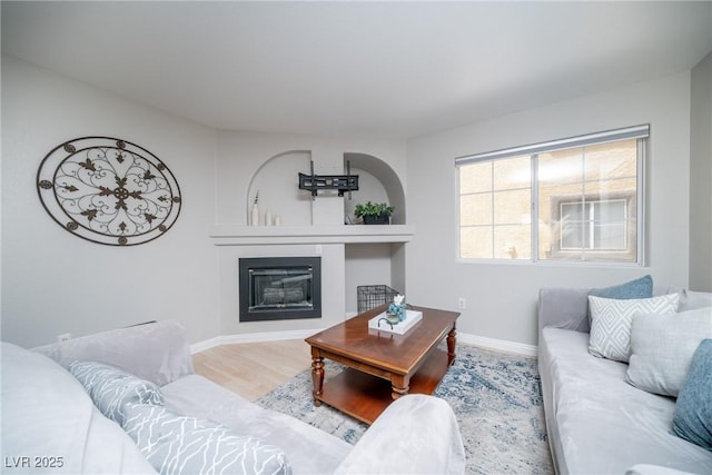 living room with baseboards, wood finished floors, and a glass covered fireplace