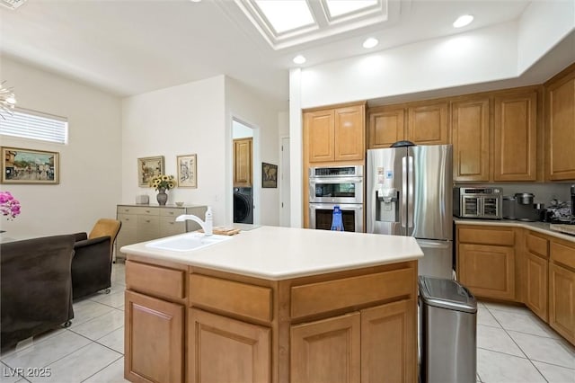 kitchen with light tile patterned floors, stainless steel appliances, washer / clothes dryer, and a sink