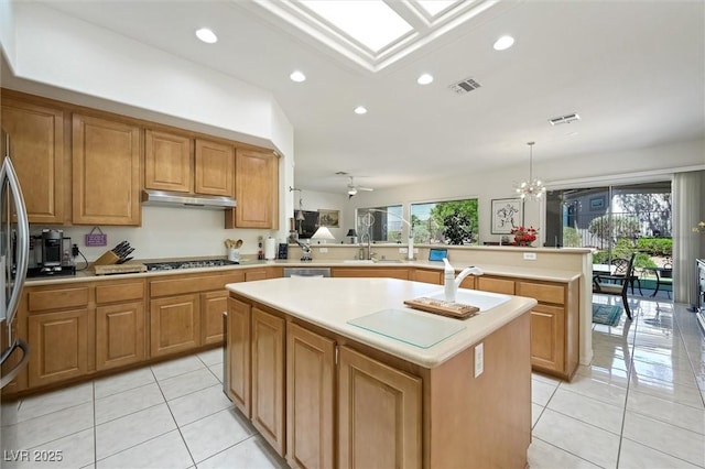 kitchen with visible vents, a center island, a peninsula, and light tile patterned flooring