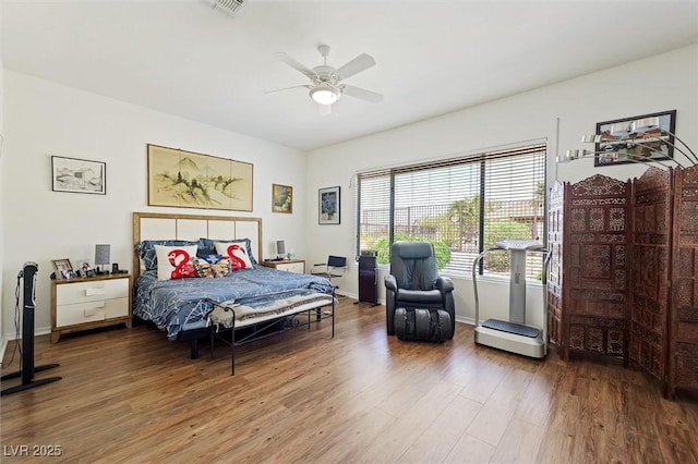 bedroom with a ceiling fan, visible vents, wood finished floors, and baseboards