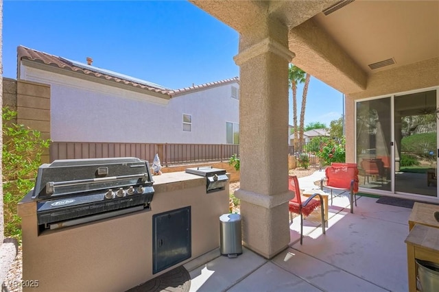view of patio featuring a grill, visible vents, exterior kitchen, and a fenced backyard