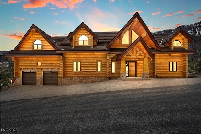 log home featuring a garage, log exterior, and dirt driveway