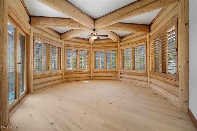 unfurnished sunroom featuring rustic walls, wood finished floors, a wealth of natural light, and beamed ceiling