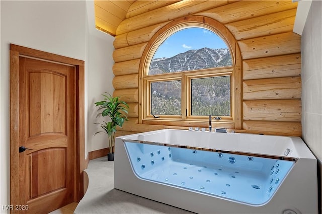 full bathroom featuring rustic walls, a mountain view, and a tub with jets