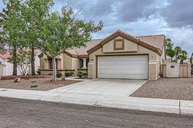mediterranean / spanish-style home featuring an attached garage, a gate, stucco siding, a tile roof, and concrete driveway
