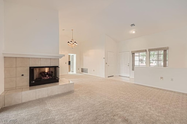 unfurnished living room featuring a tile fireplace, carpet floors, visible vents, baseboards, and a chandelier