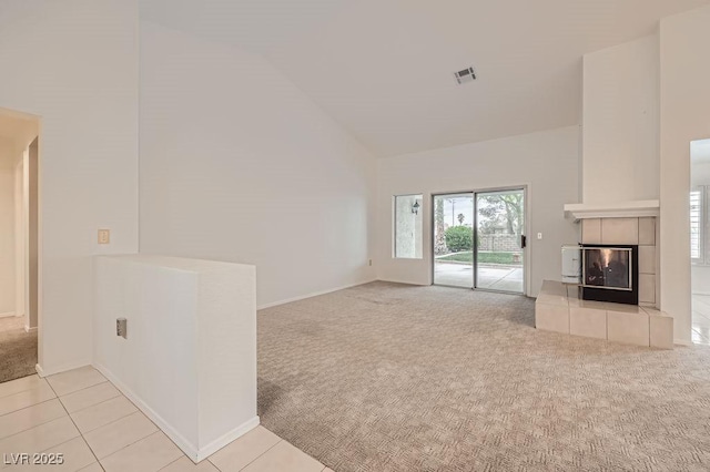unfurnished living room featuring high vaulted ceiling, visible vents, carpet floors, baseboards, and a tile fireplace