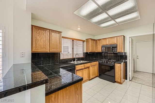 kitchen with a peninsula, light tile patterned floors, a sink, black appliances, and backsplash