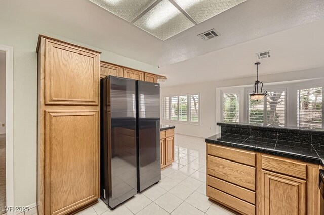 kitchen featuring freestanding refrigerator, tile counters, light tile patterned floors, and visible vents