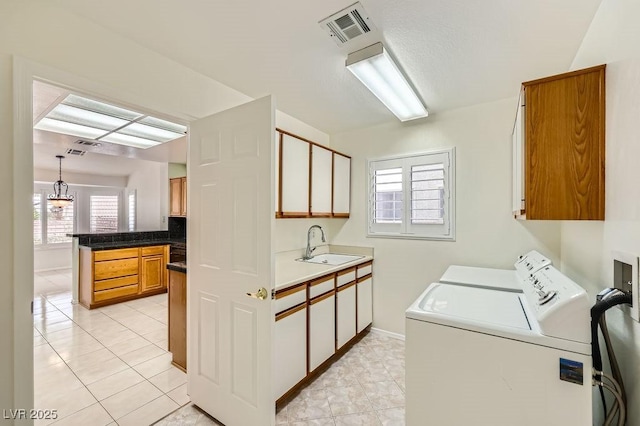 laundry area with light tile patterned flooring, a sink, visible vents, washing machine and clothes dryer, and cabinet space