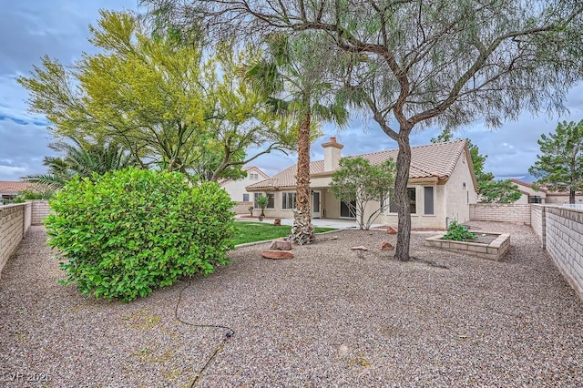 exterior space with a patio area, stucco siding, a fenced backyard, a tiled roof, and a chimney