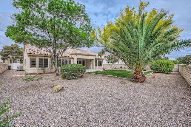 rear view of house featuring central AC unit, stucco siding, a tiled roof, and a fenced backyard