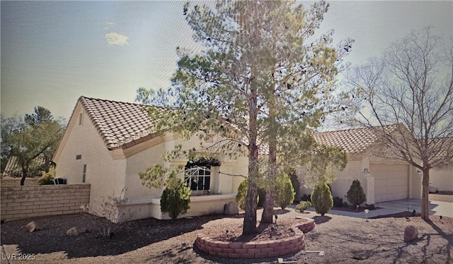 exterior space featuring concrete driveway, a tiled roof, stucco siding, and a garage