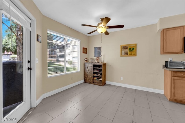 interior space with a toaster, ceiling fan, plenty of natural light, and baseboards