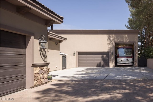 view of side of property featuring stucco siding, decorative driveway, and a tile roof
