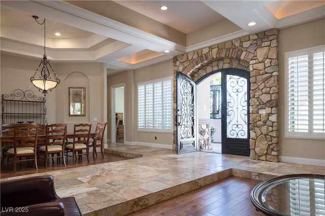 entrance foyer with arched walkways, baseboards, wood finished floors, and plenty of natural light