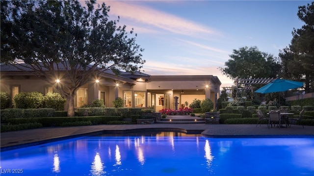 pool at dusk featuring a patio and an outdoor pool