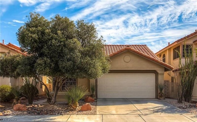 mediterranean / spanish house with a tile roof, driveway, a garage, and stucco siding