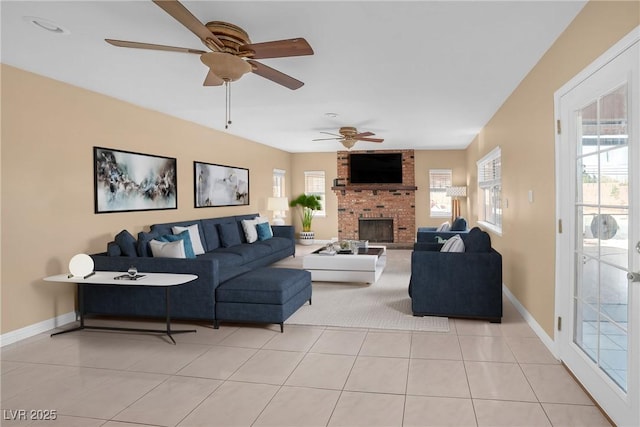 living area featuring a ceiling fan, baseboards, a healthy amount of sunlight, and a fireplace