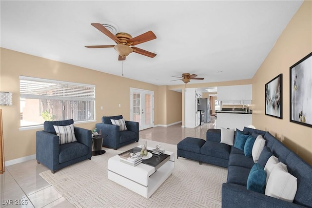 living area featuring light tile patterned floors, baseboards, ceiling fan, and french doors