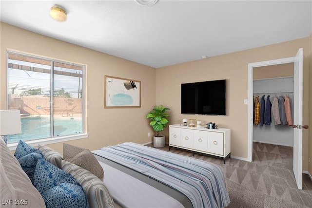 carpeted bedroom featuring baseboards, a spacious closet, and a closet