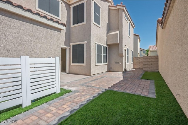 back of house with a patio, stucco siding, and a fenced backyard