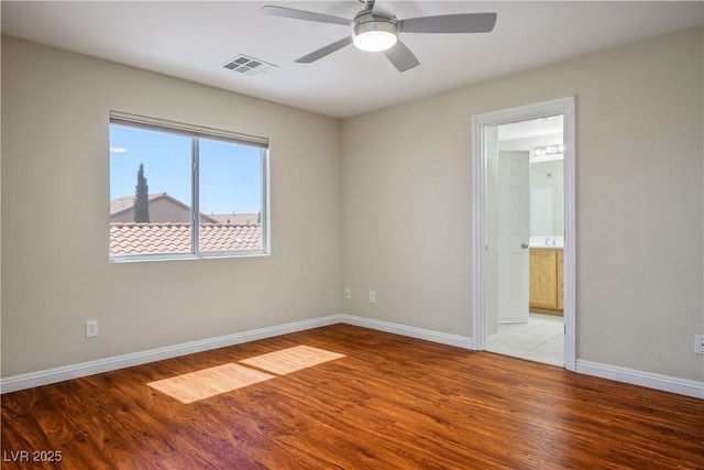 empty room with light wood finished floors, a ceiling fan, visible vents, and baseboards