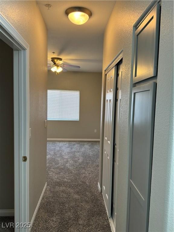 corridor with baseboards and carpet flooring