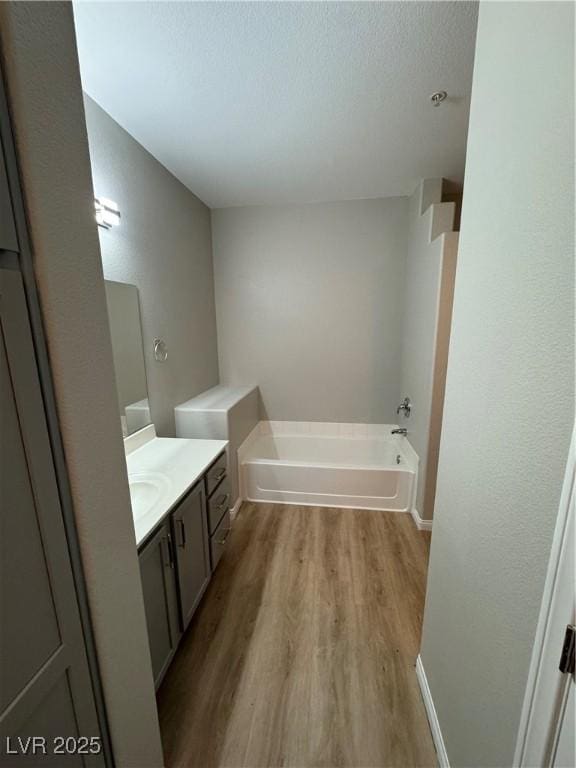 bathroom featuring wood finished floors, a garden tub, a textured ceiling, and vanity